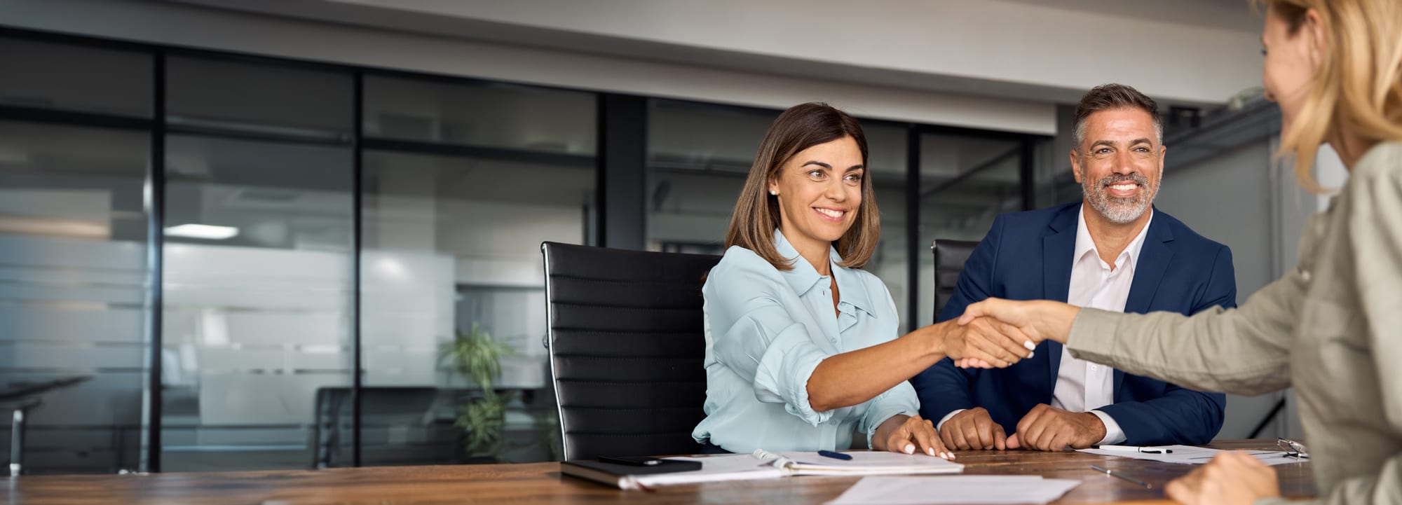 Two professionals shaking hands in a meeting — a partnership built on understanding both sides of shift-filling